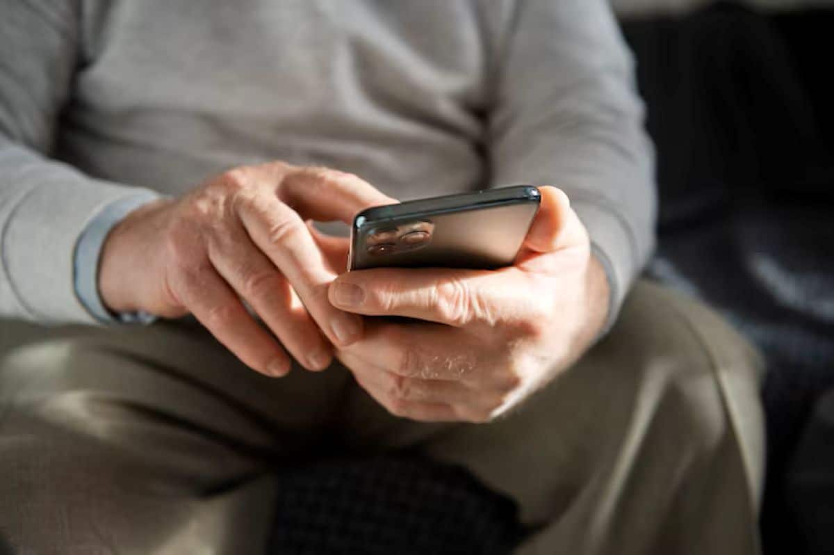 Pessoa utilizando o celular para buscar informações sobre como limpar o nome para receber aposentadoria do INSS.