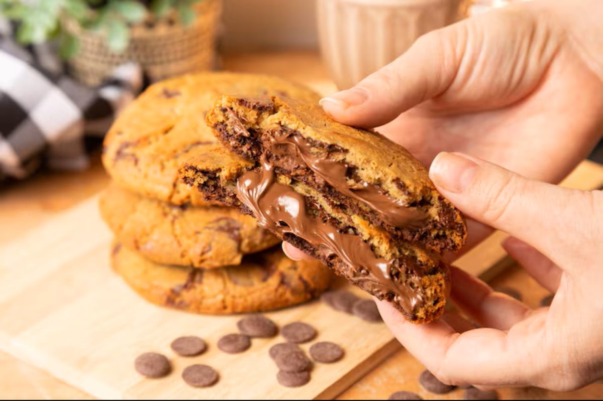 Um cookie recheado sendo partido ao meio, revelando um cremoso recheio de chocolate derretido, ideal para personalizar receitas.