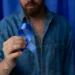 Homenagem ao Novembro Azul: Homem segurando fita azul, símbolo da luta contra o câncer de próstata, em ambiente com fundo azul.