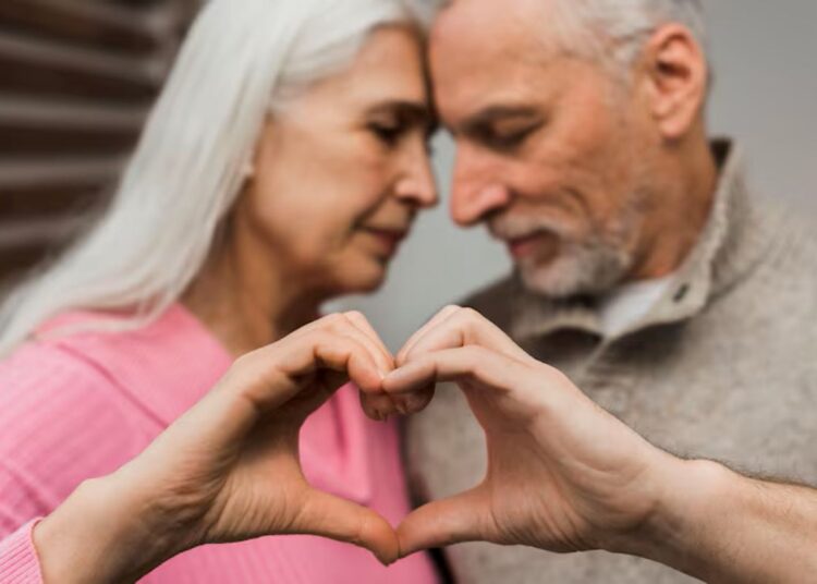 Casal idoso demonstrando carinho e formando um coração com as mãos
