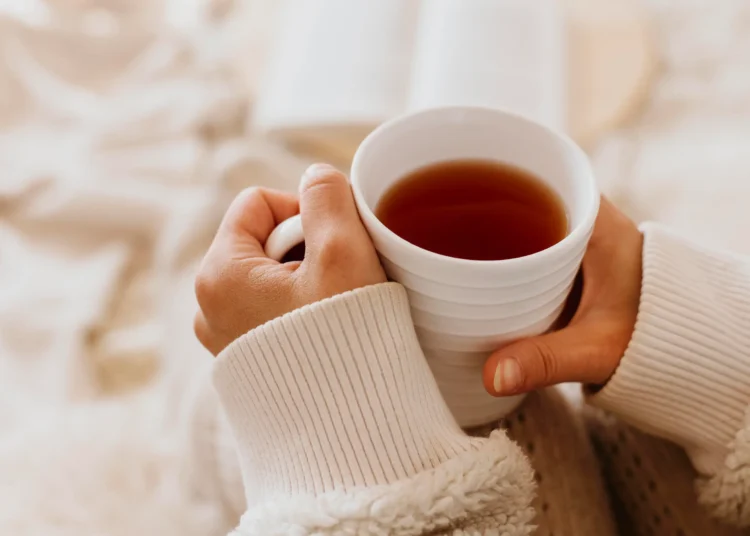 Mãos segurando uma xícara de chá quente, simbolizando o uso de bebidas herbais para combater a insônia.