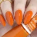 Unhas com esmalte laranja vibrante, tendência de cor para 2026.