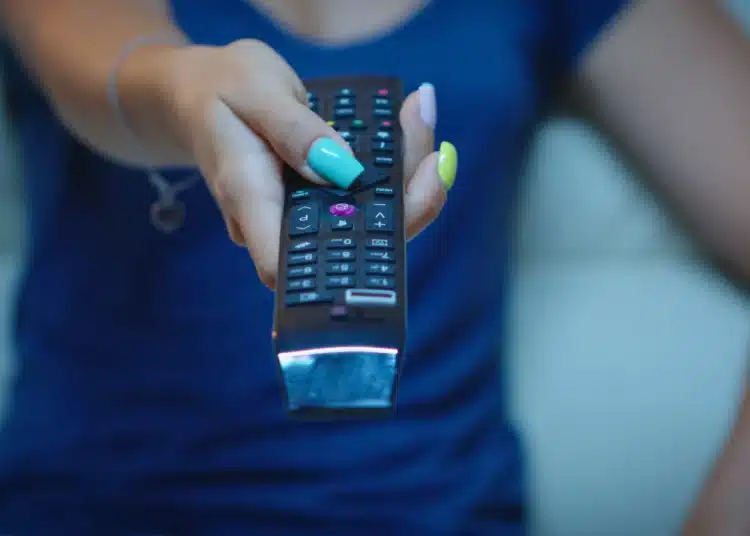 Pessoa usando controle remoto para procurar soluções sobre queda de IPTV no Reclame Aqui.