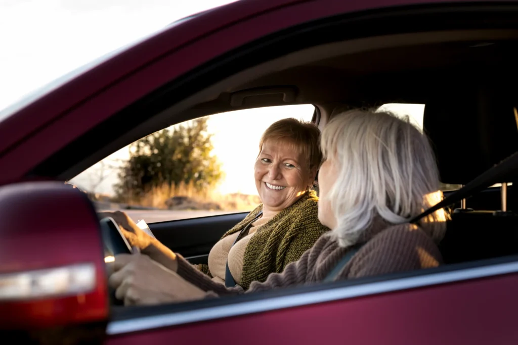 Idosas sorrindo dentro de um carro, refletindo a importância da mobilidade para a autonomia na terceira idade.