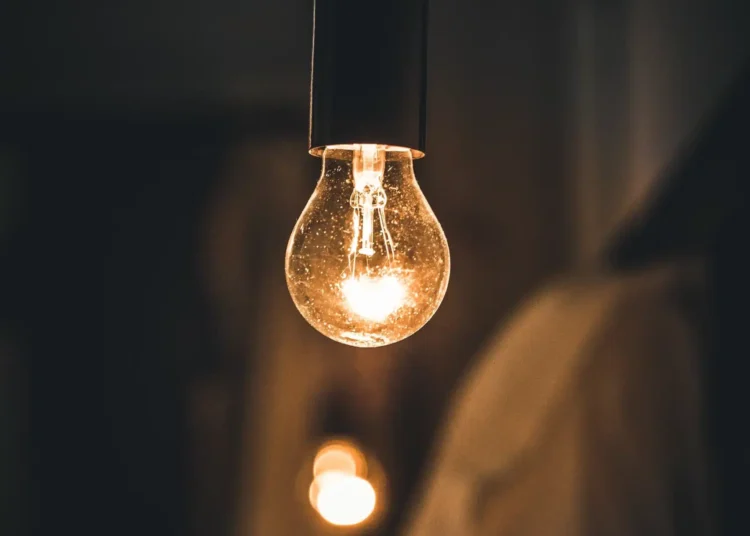 Lâmpada acesa em ambiente escuro simbolizando o novo programa Luz do Povo,