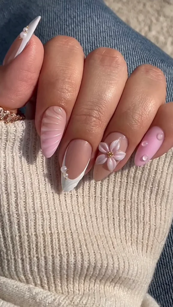 Unhas decoradas em rosa e branco com flor 3D e aplicação de pérolas.