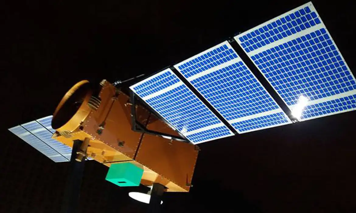 Imagem de satélite com painéis solares brilhando em órbita ao redor da Terra