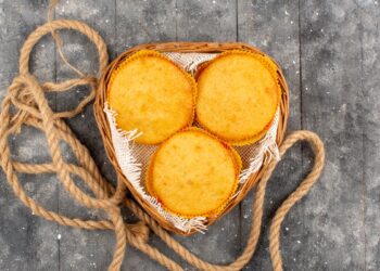 Três broas redondas de fubá com queijo dentro de uma cesta rústica, prontas para servir, destacando a cor amarelada e o aspecto caseiro.