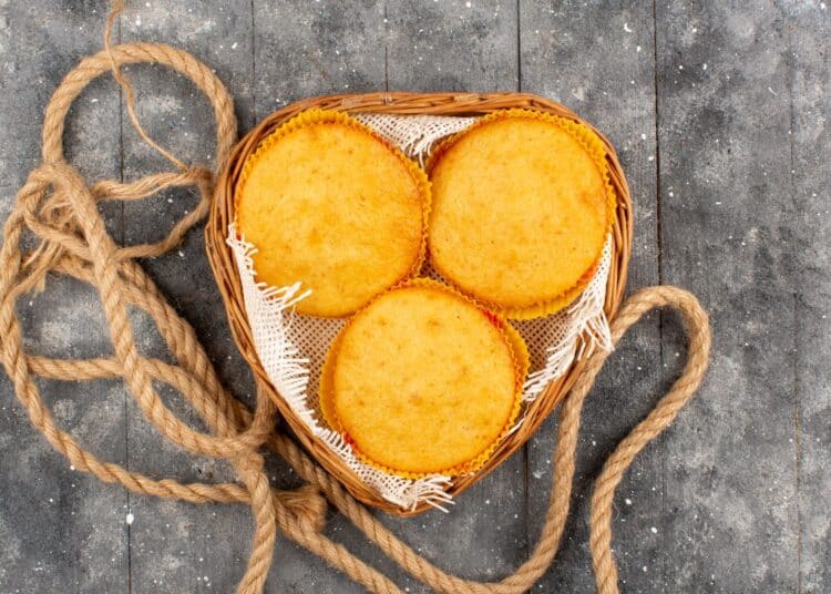 Três broas redondas de fubá com queijo dentro de uma cesta rústica, prontas para servir, destacando a cor amarelada e o aspecto caseiro.