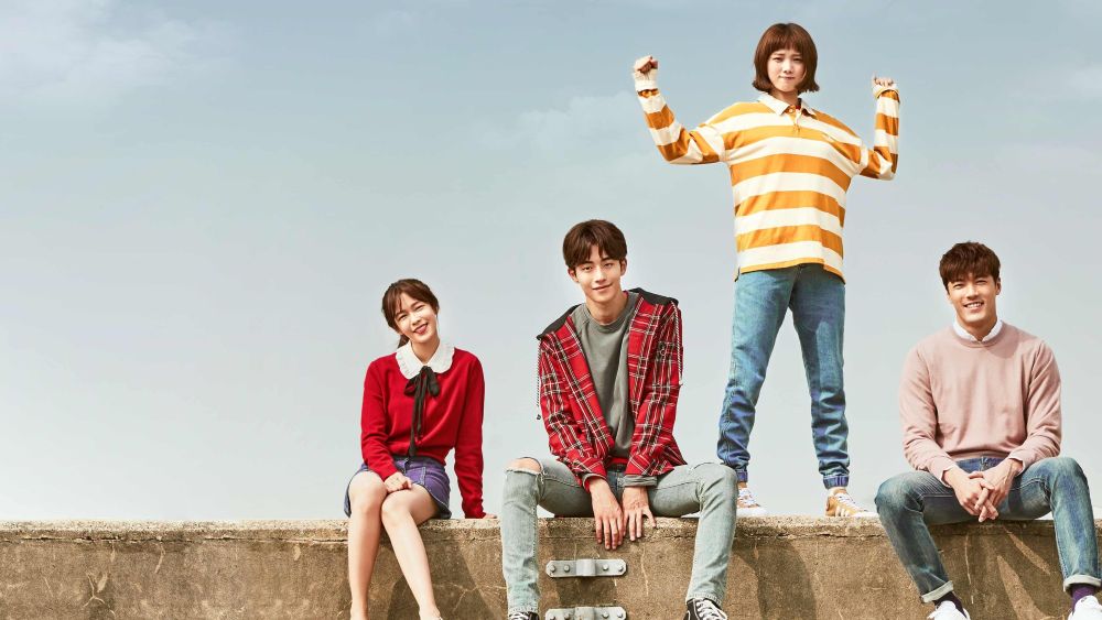 Os cinco personagens principais de Fada do Levantamento de Peso sentados sobre um muro de concreto sob um céu azul limpo, incluindo Bok-joo e Joon-hyung.