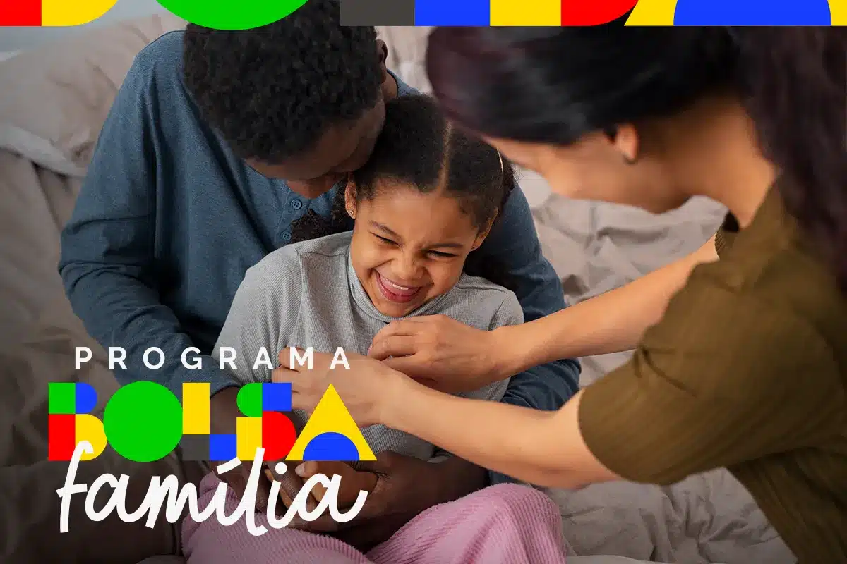 Família alegre com dois adultos e uma criança sorridente sentados em cama, representando o Bolsa Família