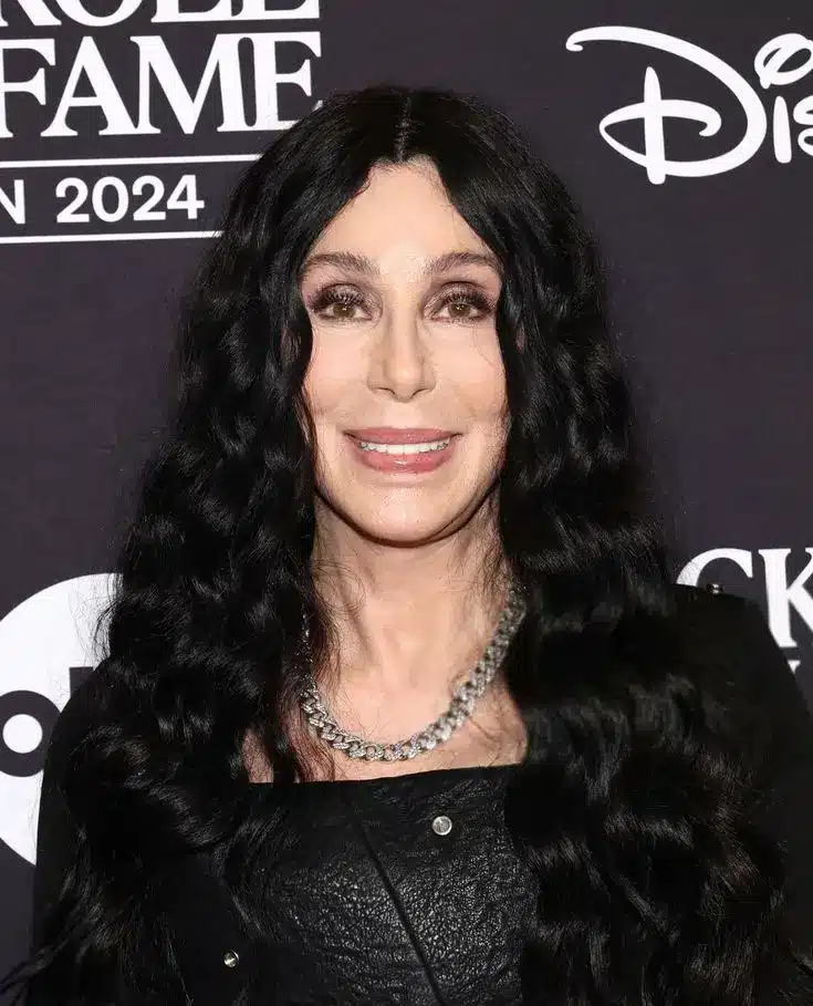 Cher com cabelo volumoso e cacheado, visual marcante dos anos 80 com permanente e máximo volume.