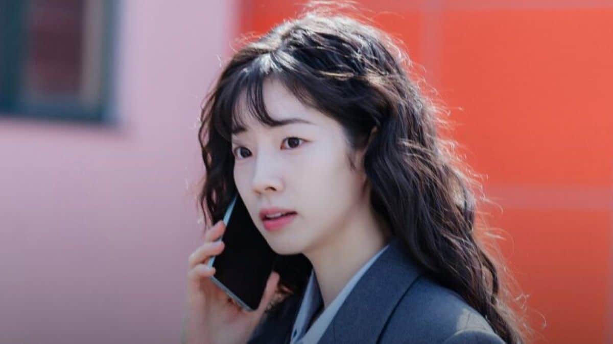 Cena de Love Me, mostrando a personagem principal, interpretada por Dahyun, falando ao telefone com expressão preocupada em cenário urbano.