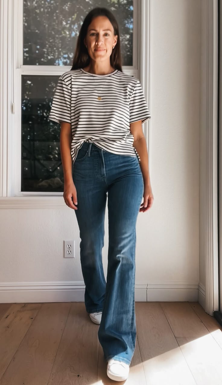 Mulher usando jeans flare (calça boca de sino) de cintura alta com camiseta listrada, valorizando a silhueta