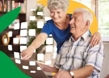 Casal de idosos felizes usando um laptop com orientação em ambiente doméstico