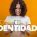 Mulher sorrindo segurando sua nova carteira de identidade, com fundo laranja. A nova identidade é projetada para reduzir fraudes em até dez vezes, conforme estudo recente.