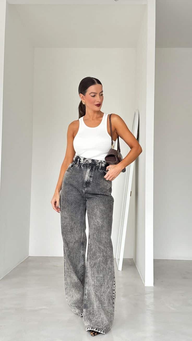 Mulher usando calça jeans cinza larga (wide leg) de cintura alta em look urbano e moderno