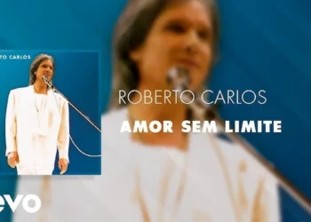 Roberto Carlos em performance ao vivo, com fundo azul e traje branco, representando o clima romântico da canção 'Amor Sem Limite'.