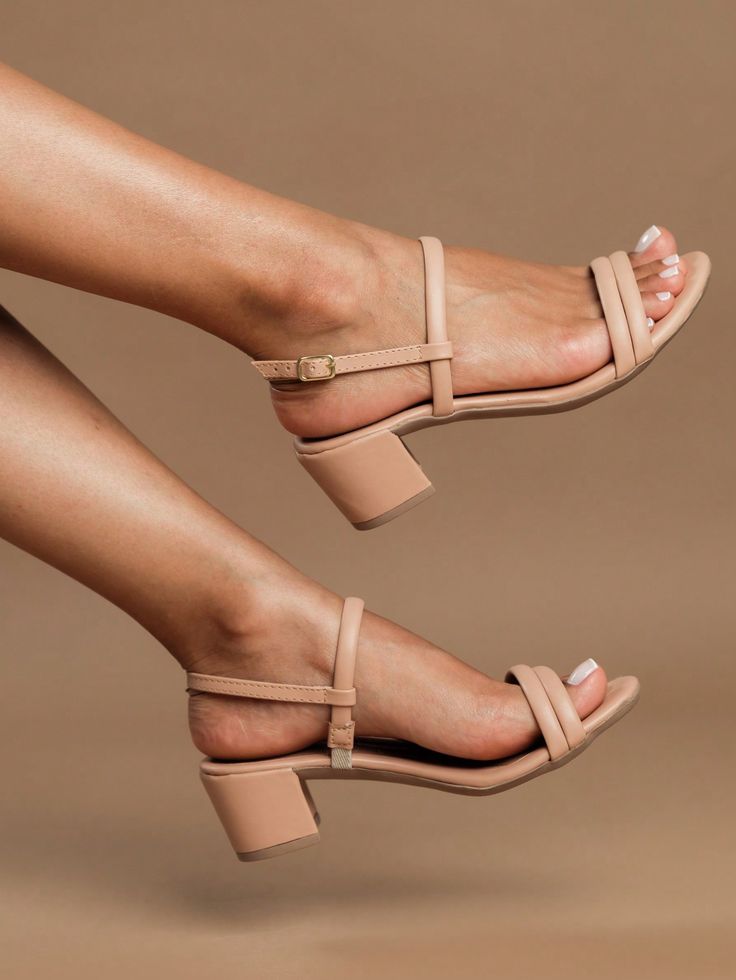 Sandália de salto bloco (ilustrada aqui por um salto fino similar) na cor nude, conhecida por alongar as pernas. O modelo oferece conforto e estabilidade.