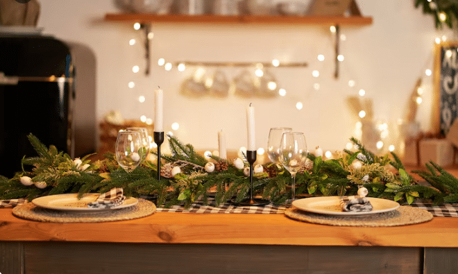 Mesa de madeira decorada para Natal com velas brancas, folhas verdes, bolas de Natal e pratos rústicos