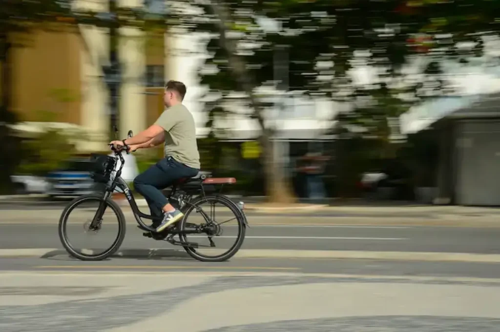 Homem conduzindo bicicleta elétrica equipada com acelerador, destacando mudanças nas regras que a classificam como ciclomotor.