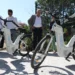 Bicicletas elétricas brancas movidas a hidrogênio expostas com pessoas observando ao fundo