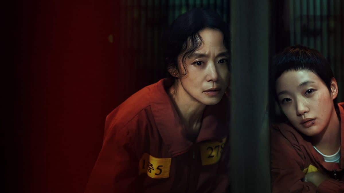 Cena do dorama The Price of Confession, mostrando duas mulheres em uma atmosfera tensa e sombria, com trajes laranja de presidiárias.