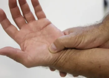 Pessoa segurando o pulso com a mão direita demonstrando dor ou desconforto no punho