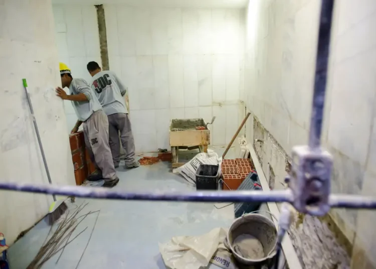 Homem segurando cofrinho rosa e notas de 100 reais, promovendo poupança para ensino médio