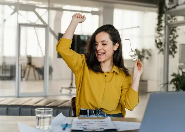 Mulher comemorando conquista profissional em ambiente de trabalho moderno, simbolizando sucesso em 2026.