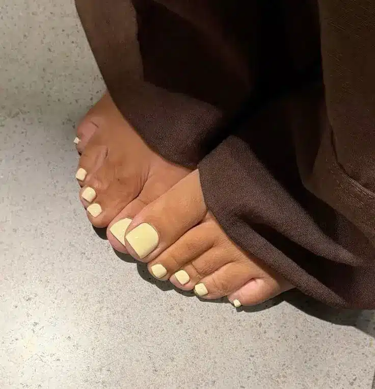 Unhas dos pés em tom amarelo manteiga com acabamento suave e sofisticado.