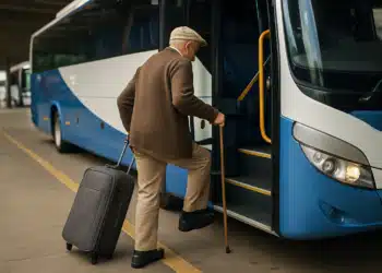 Idoso embarcando em ônibus com mala de viagem.