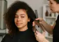 Cabeleireira cortando o cabelo de uma jovem com cabelo cacheado