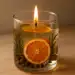 Vela aromática artesanal em copo de vidro com fatia de laranja, alecrim e especiarias