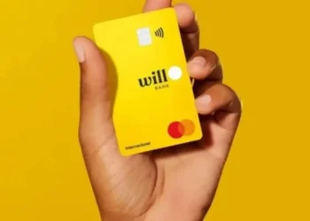 Cartão amarelo do Will Bank sendo exibido por uma mão, fundo amarelo