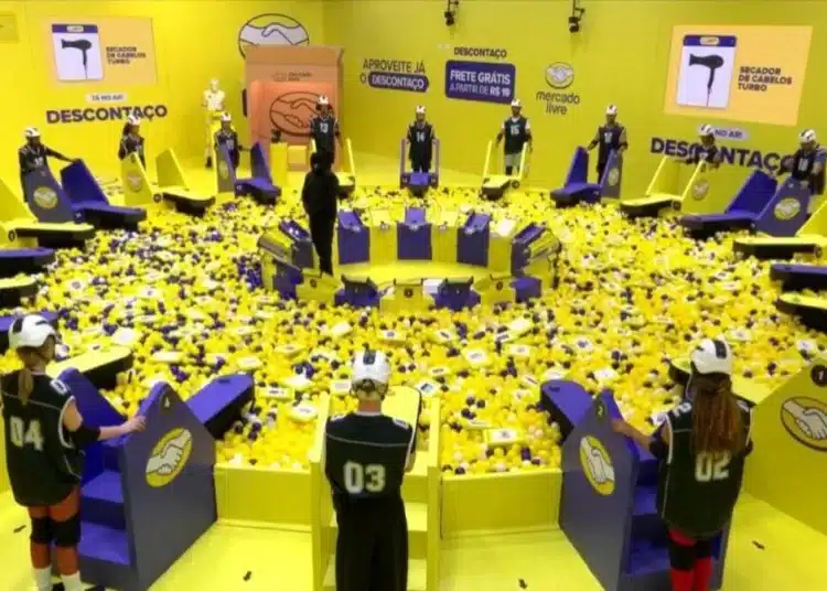 Participantes do BBB26 enfrentam prova de resistência com bolas amarelas em um cenário amarelo e roxo.