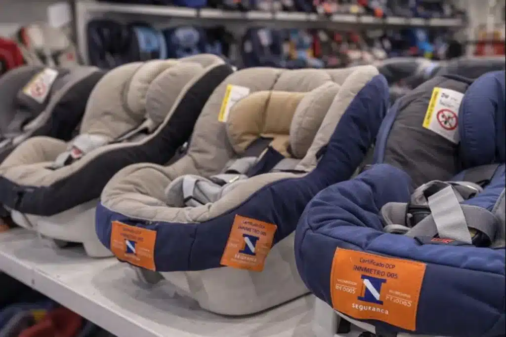 Conjunto de bebê conforto com selo de certificação Inmetro, expostos em prateleira de loja, evidenciando a segurança e as recomendações para o uso correto do dispositivo.