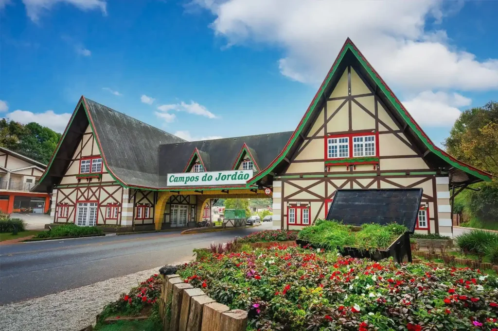Entrada turística de Campos do Jordão com arquitetura no estilo enxaimel e jardim florido.