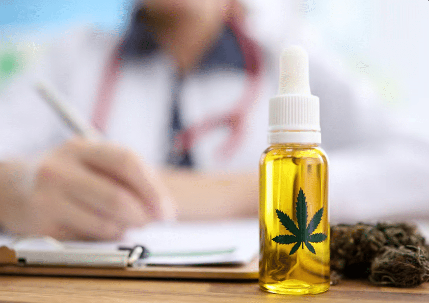 Close-up de um frasco de óleo de cannabis medicinal dourado com conta-gotas e o desenho de uma folha de cannabis em destaque, colocado sobre uma mesa de madeira. Ao fundo, um médico desfocado escreve em uma prancheta, sugerindo uma consulta ou prescrição. Ao lado do frasco, há uma pequena pilha de flores secas de cannabis.
