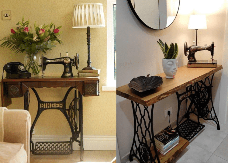 Máquina de costura Singer antiga de pedal com a base de ferro trabalhada e um tampo de madeira, transformada em um aparador com vaso de flores, luminária e telefone retrô.