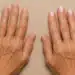 Mãos femininas com unhas naturais e unhas pintadas com esmalte nude