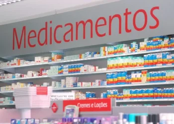 Prateleiras organizadas com caixas de medicamentos em farmácia, com destaque para a placa "Medicamentos".