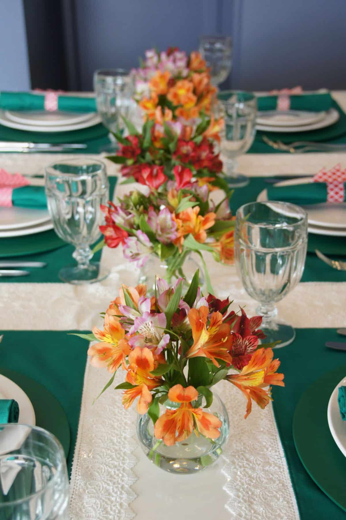 Mesa posta com arranjos de flores coloridas e utensílios organizados