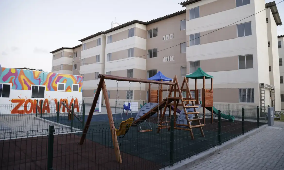 Playground cercado em condomínio residencial popular com prédios ao fundo