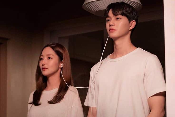 Casal de jovens dividindo fones de ouvido, lado a lado, em ambiente aconchegante