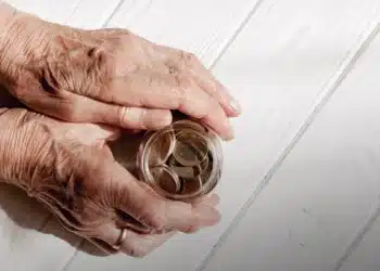 Idosa segurando um potinho de moedas.