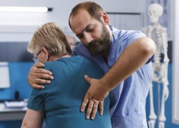 Profissional faz manobra na coluna de mulher idosa usando técnica de fisioterapia.