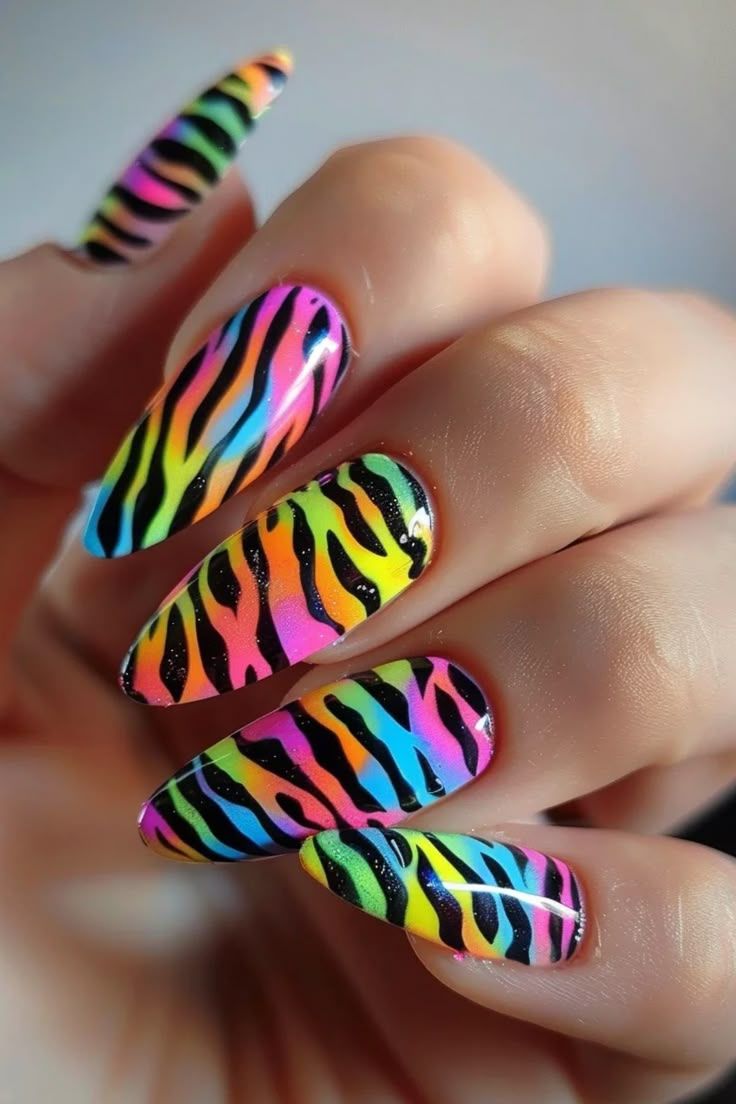 Mão exibe unhas longas decoradas com listras coloridas em padrão animal.