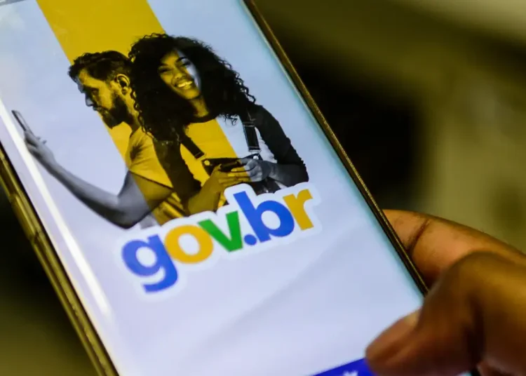 Pessoa segura smartphone exibindo tela do aplicativo gov.br com imagens de duas pessoas sorrindo
