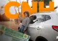 Jovem sorridente segura chave ao lado de carro branco com CNH em destaque.